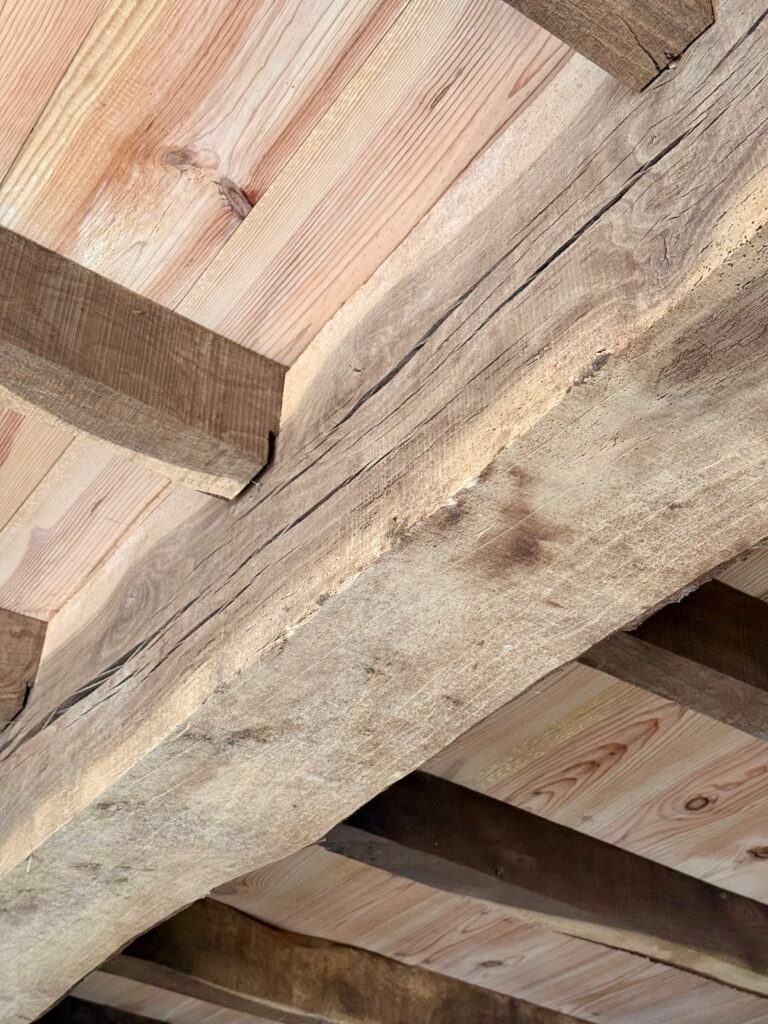 Assemblage de poutres en bois d'un plancher chevronné dans une ferme basque – charpente traditionnelle Maison Lardeux
