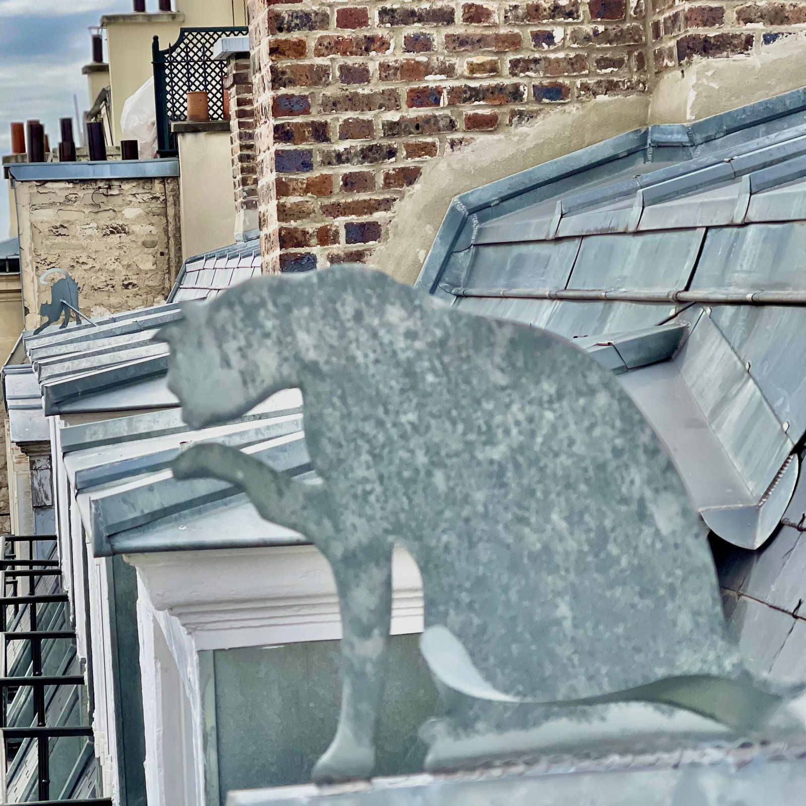 Ornement en zinc en forme de chat sur une toiture parisienne – zinguerie d'art Maison Lardeux
